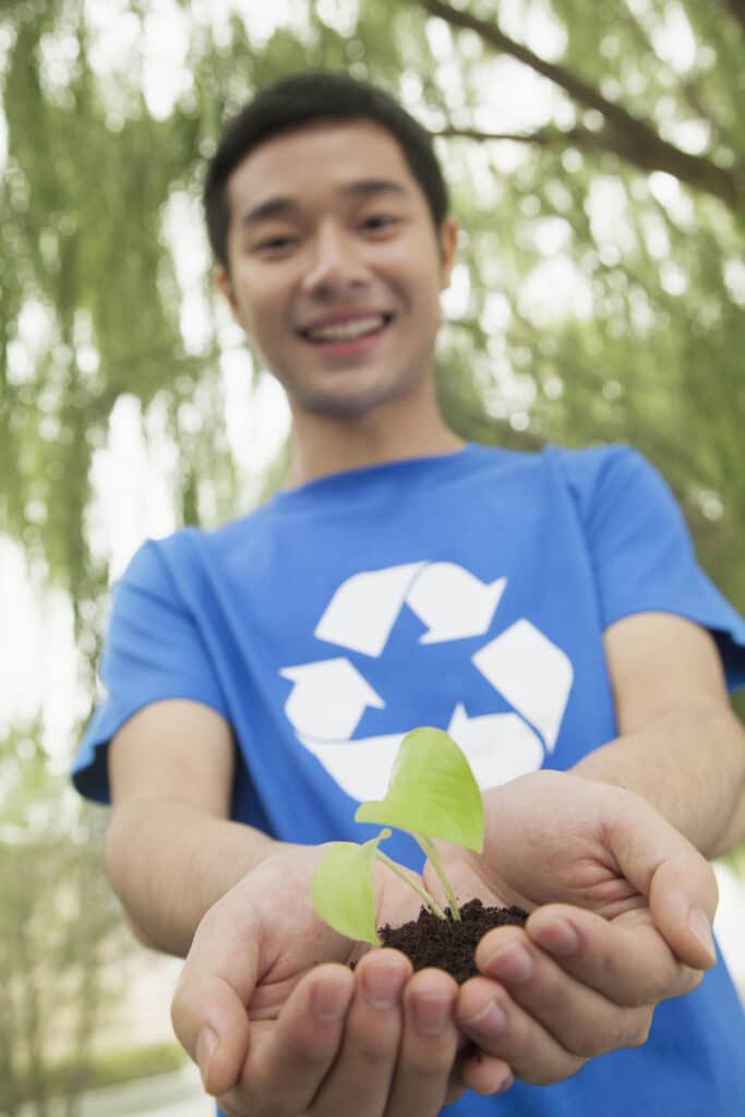 Young Man Holding Seedling in his Hands, Recycling Symbol, Low Angle View